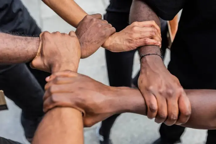 Group of friends joining hands together outdoors